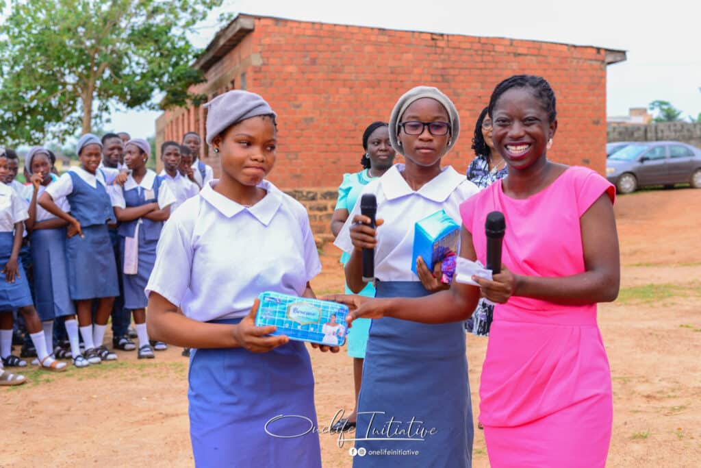 two students being handed sanitary pads 